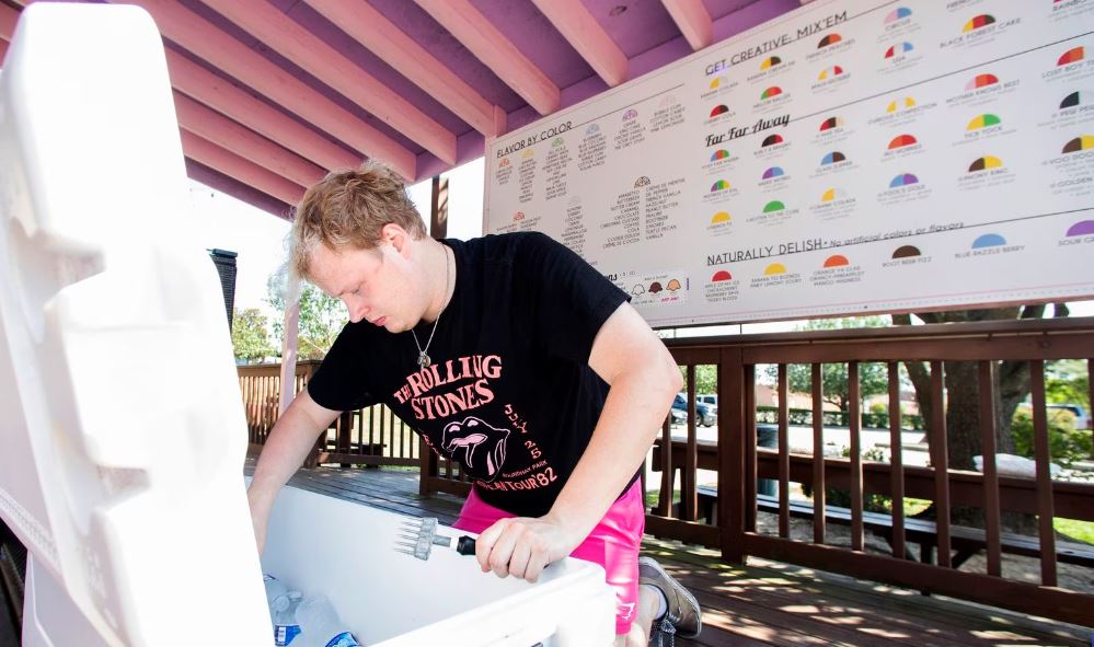 Cole Matlock apila hielo para enfriar agua para los clientes de su negocio, Lottie's Shivers Shaved Ice, el martes 27 de junio de 2023, en Conroe, Texas.(Jason Fochtman / ASSOCIATED PRESS)