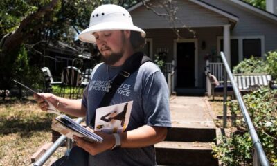 El cartero Rhett Hanes usa un gorro para protegerse de los ataques de halcones mientras entrega el correo en Milan Place y Kenwood Ave. en Travis Heights, el 12 de julio de 2023, en Austin. El Servicio Postal de Estados Unidos ha suspendido la entrega de correo en el área por los repetidos ataques de dichas aves en lo que va del mes.(Kara Hawley)