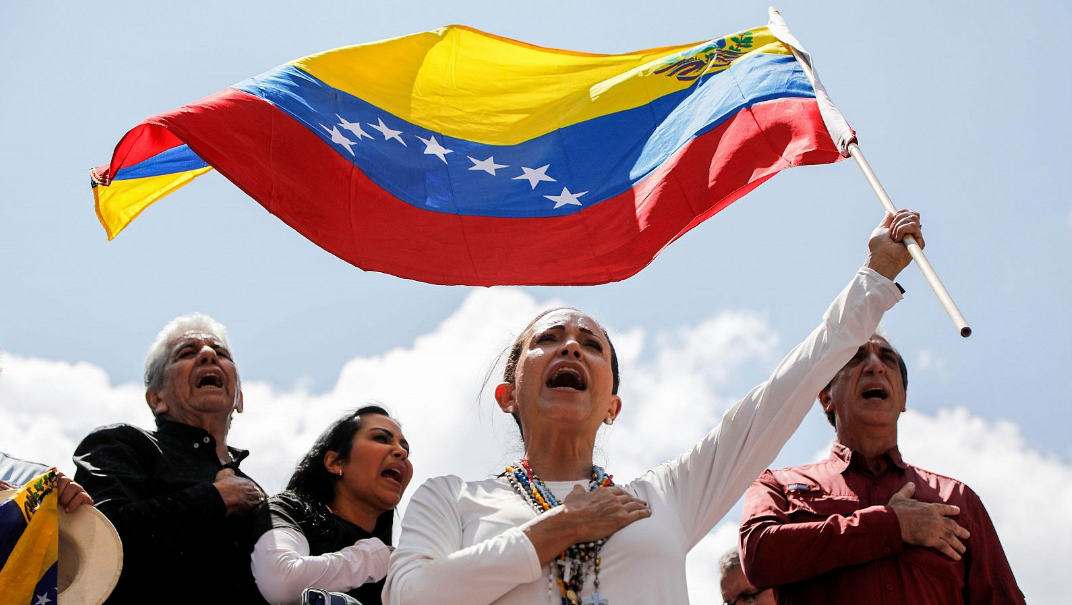 La líder opositora venezolana María Corina Machado ondea una bandera durante una manifestación en Caracas AP/Cristián Hernández