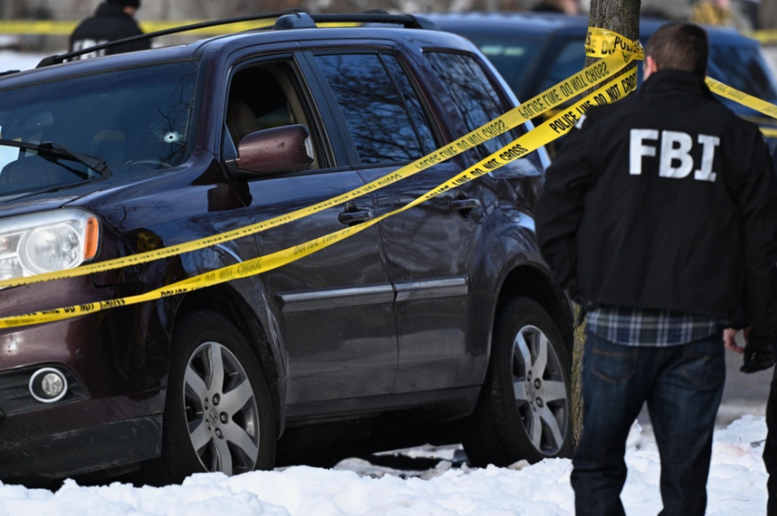 Agentes federales en la escena del tiroteo en Minneapolis, junto a un parabrisas baleado. (Foto AP/Tom Baker)