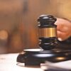 Close-up of a black gavel with a gold band resting on a wooden judge's bench, symbolizing a court ruling