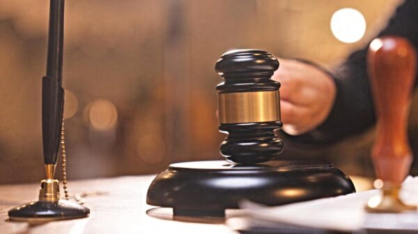 Close-up of a black gavel with a gold band resting on a wooden judge's bench, symbolizing a court ruling