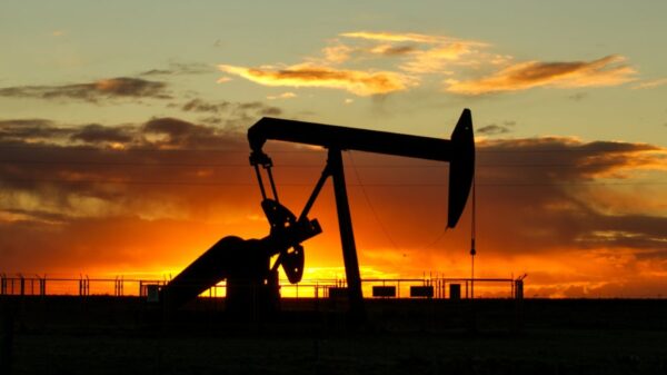 Silhouette of an oil pumpjack against a orange sunset sky.