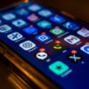 Close-up of a smartphone screen in low light showing glowing app icons on the home screen (Chrome, Gmail, ChatGPT, Messages, etc.).