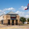 Front view of Bailey Middle School with a digital sign saying 'Home of the Bears' and a flagpole displaying the U.S. and Texas flags against a bright blue sky.