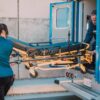 Paramedics load a patient stretcher into an ambulance to transport.