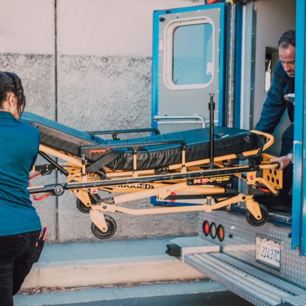 Paramedics load a patient stretcher into an ambulance to transport.