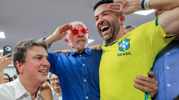 Group of men celebrating together; one wears a Brazil yellow jersey, others smile and pose for a selfie.