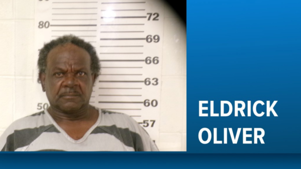 Mugshot of Eldrick Oliver standing before a height chart, with a blue banner showing his name on the right.