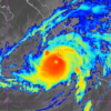 Tropical cyclone with a distinct eye, bright red center and surrounding yellow and blue rain bands on a satellite radar map.