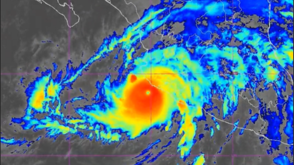 Tropical cyclone with a distinct eye, bright red center and surrounding yellow and blue rain bands on a satellite radar map.