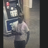 Grainy security cam image of a person in a light shirt and dark pants standing near equipment.