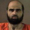 Bearded man in an orange jail jumpsuit facing the camera in a mugshot-style photo.