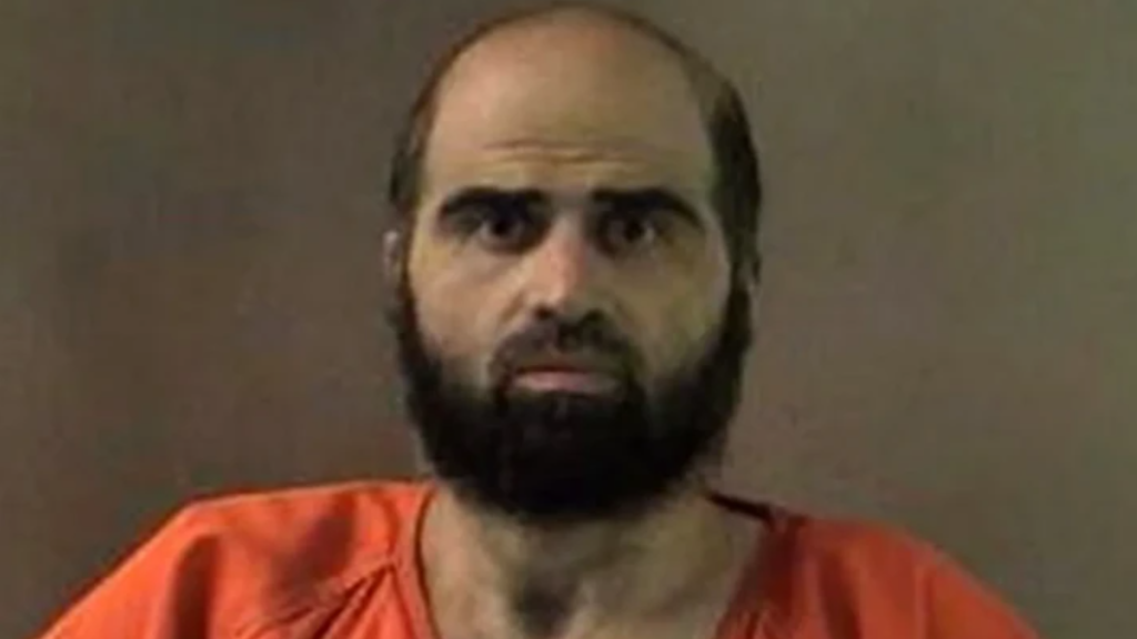 Bearded man in an orange jail jumpsuit facing the camera in a mugshot-style photo.