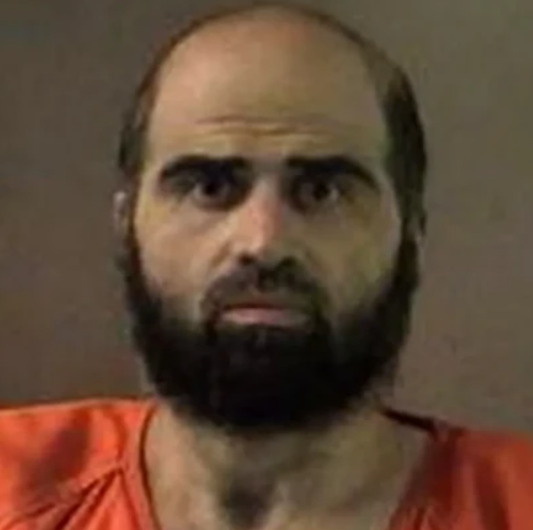 Bearded man in an orange jail jumpsuit facing the camera in a mugshot-style photo.