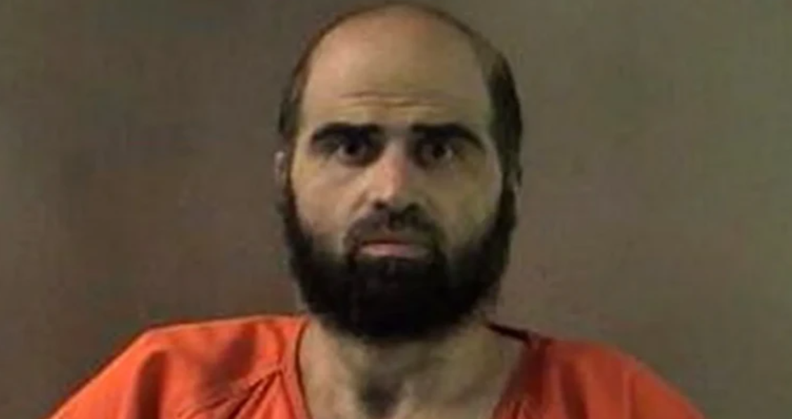 Bearded man in an orange jail jumpsuit facing the camera in a mugshot-style photo.