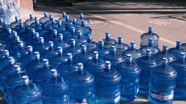 Row of large blue water jugs lined up outdoors, likely for water distribution or emergency supply.