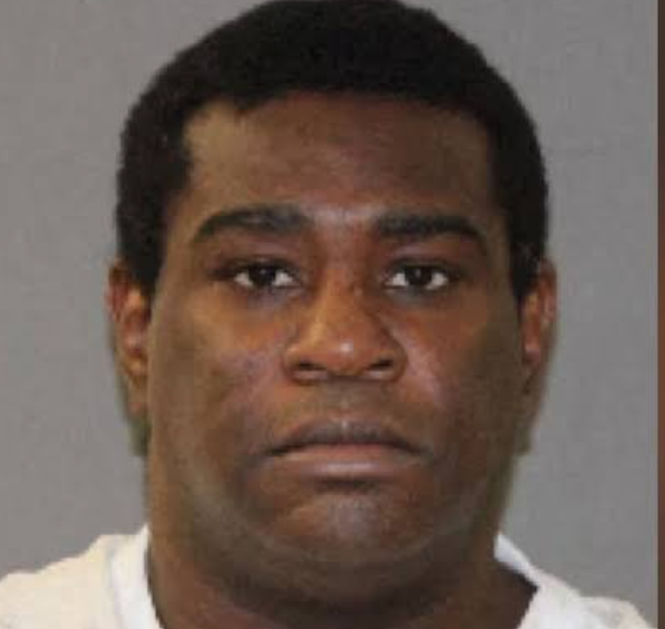 Mugshot of a Black man with short black hair wearing a white shirt against a gray backdrop with a neutral expression.